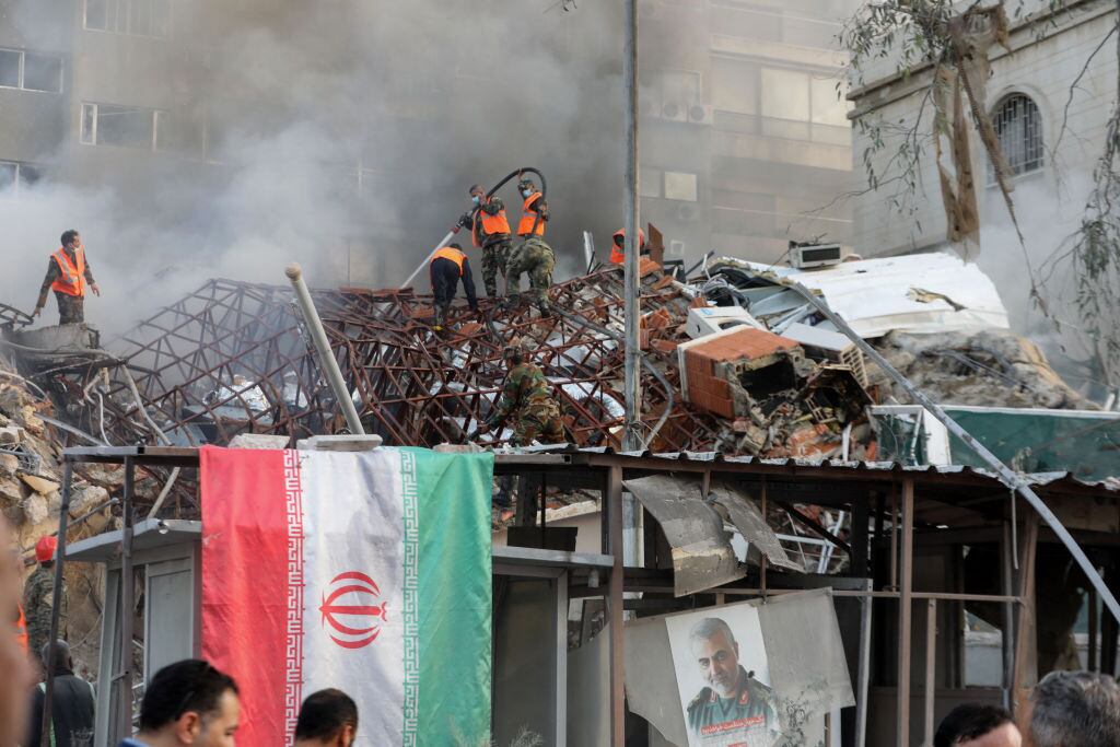 Personal de emergencia busca entre los escombros del edificio bombardeado junto a la embajada de Irán en Siria.