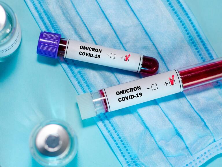 Test tube with positive Omicron COVID-19 test blood sample and vaccine bottle in the medical laboratory.