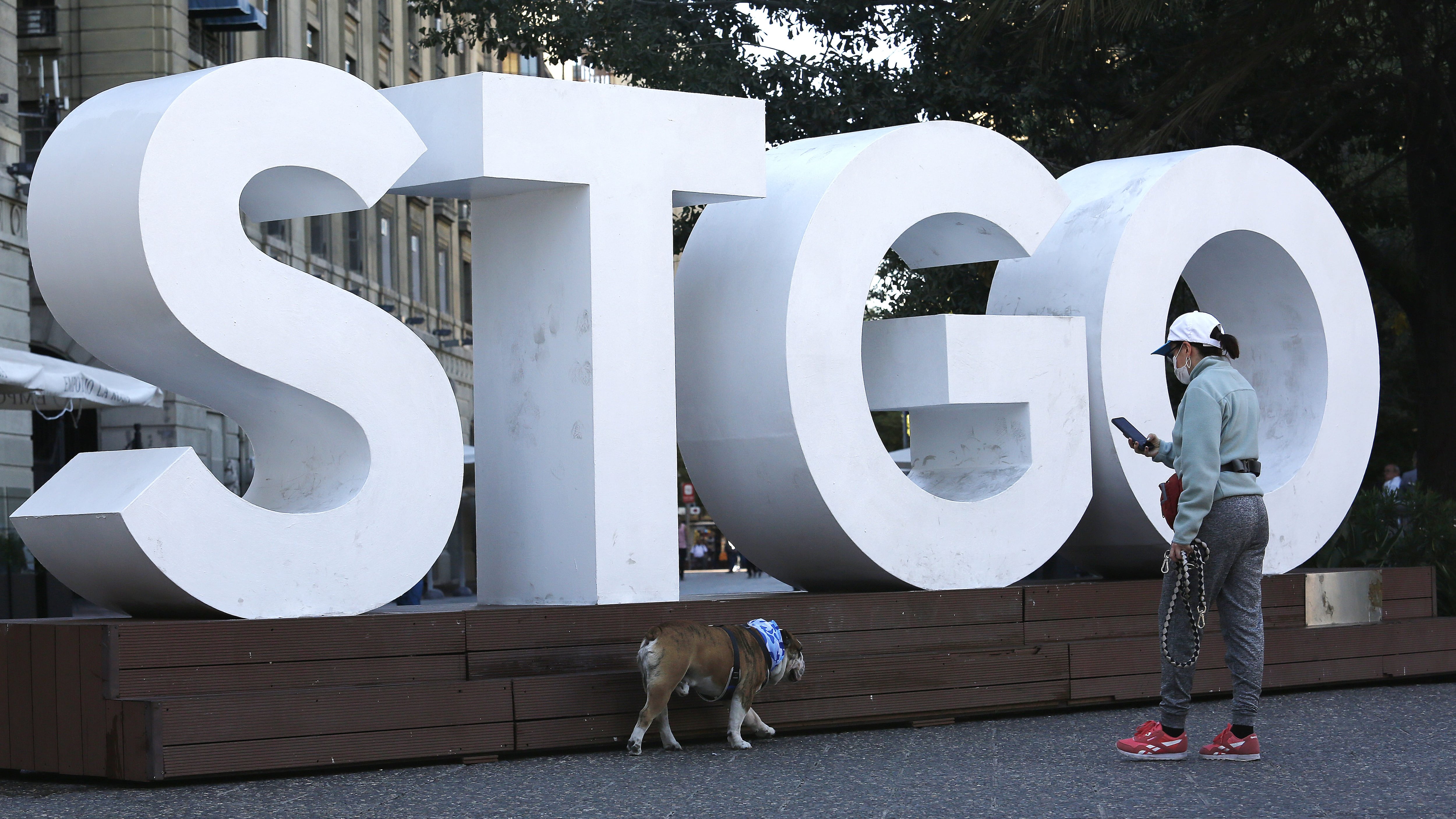 SANTIAGO, CHILE - MARCH 24: A woman wearing a face mask takes photos of her dog during the covid-19 pandemic on March 24, 2020 in Santiago, Chile. The "state of catastrophe" declared by president Sebastian Piñera gives the government extraordinary powers to restrict freedom of movement and assure food supply and basic services for 90 days to confront the spread of COVID-19. (Photo by Marcelo Hernandez/Getty Images)