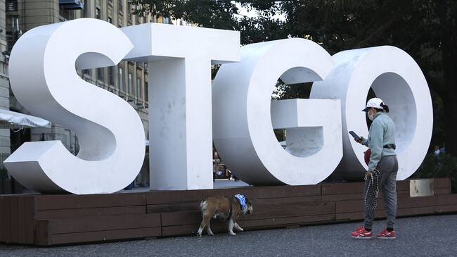 SANTIAGO, CHILE - MARCH 24: A woman wearing a face mask takes photos of her dog during the covid-19 pandemic on March 24, 2020 in Santiago, Chile. The "state of catastrophe" declared by president Sebastian Piñera gives the government extraordinary powers to restrict freedom of movement and assure food supply and basic services for 90 days to confront the spread of COVID-19. (Photo by Marcelo Hernandez/Getty Images)