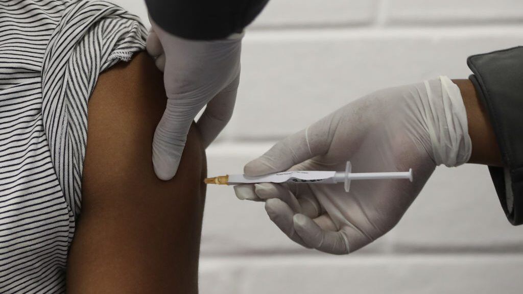 One of the first South African Oxford vaccine trialists looks on as a medical worker injects him with the clinical trial for a potential vaccine against the COVID-19 coronavirus at the Baragwanath hospital in Soweto, South Africa, on June 24 ,2020. (Photo by SIPHIWE SIBEKO / POOL / AFP) (Photo by SIPHIWE SIBEKO/POOL/AFP via Getty Images)