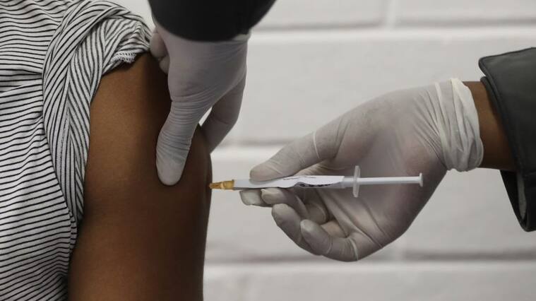 One of the first South African Oxford vaccine trialists looks on as a medical worker injects him with the clinical trial for a potential vaccine against the COVID-19 coronavirus at the Baragwanath hospital in Soweto, South Africa, on June 24 ,2020. (Photo by SIPHIWE SIBEKO / POOL / AFP) (Photo by SIPHIWE SIBEKO/POOL/AFP via Getty Images)