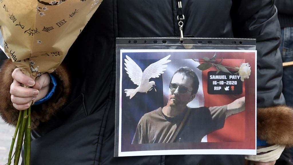 TOPSHOT - A woman holds a picture of Samuel Paty, Place de la Liberte in Lille on October 18, 2020, in homage to the history teacher, two days after he was beheaded by an attacker who was shot dead by policemen. - Thousands of people rally in Paris and other French cities on October 18 in a show of solidarity and defiance after a teacher was beheaded for showing pupils cartoons of the Prophet Mohammed. His murder in a Paris suburb on October 16 shocked the country and brought back memories of a wave of Islamist violence in 2015. (Photo by FRANCOIS LO PRESTI / AFP) (Photo by FRANCOIS LO PRESTI/AFP via Getty Images)