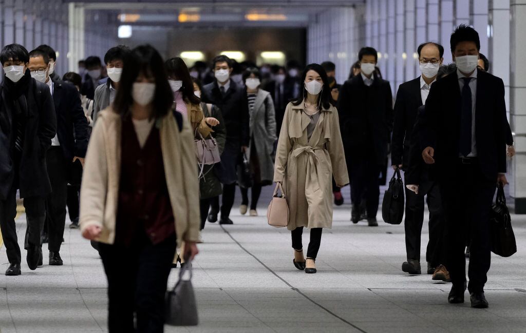 Los trabajadores utilizan máscaras en las calles de la ciudad de Tokio