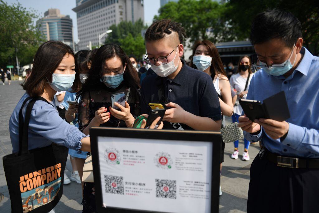 TOPSHOT - People wear face masks as a preventive measure against the COVID-19 coronavirus as they use a phone app to scan a code required to prove their health and travel status before being allowed to enter a shopping mall in Beijing on May 2, 2020, the second day of a five-day national holiday. (Photo by GREG BAKER / AFP) (Photo by GREG BAKER/AFP via Getty Images)