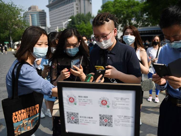 TOPSHOT - People wear face masks as a preventive measure against the COVID-19 coronavirus as they use a phone app to scan a code required to prove their health and travel status before being allowed to enter a shopping mall in Beijing on May 2, 2020, the second day of a five-day national holiday. (Photo by GREG BAKER / AFP) (Photo by GREG BAKER/AFP via Getty Images)