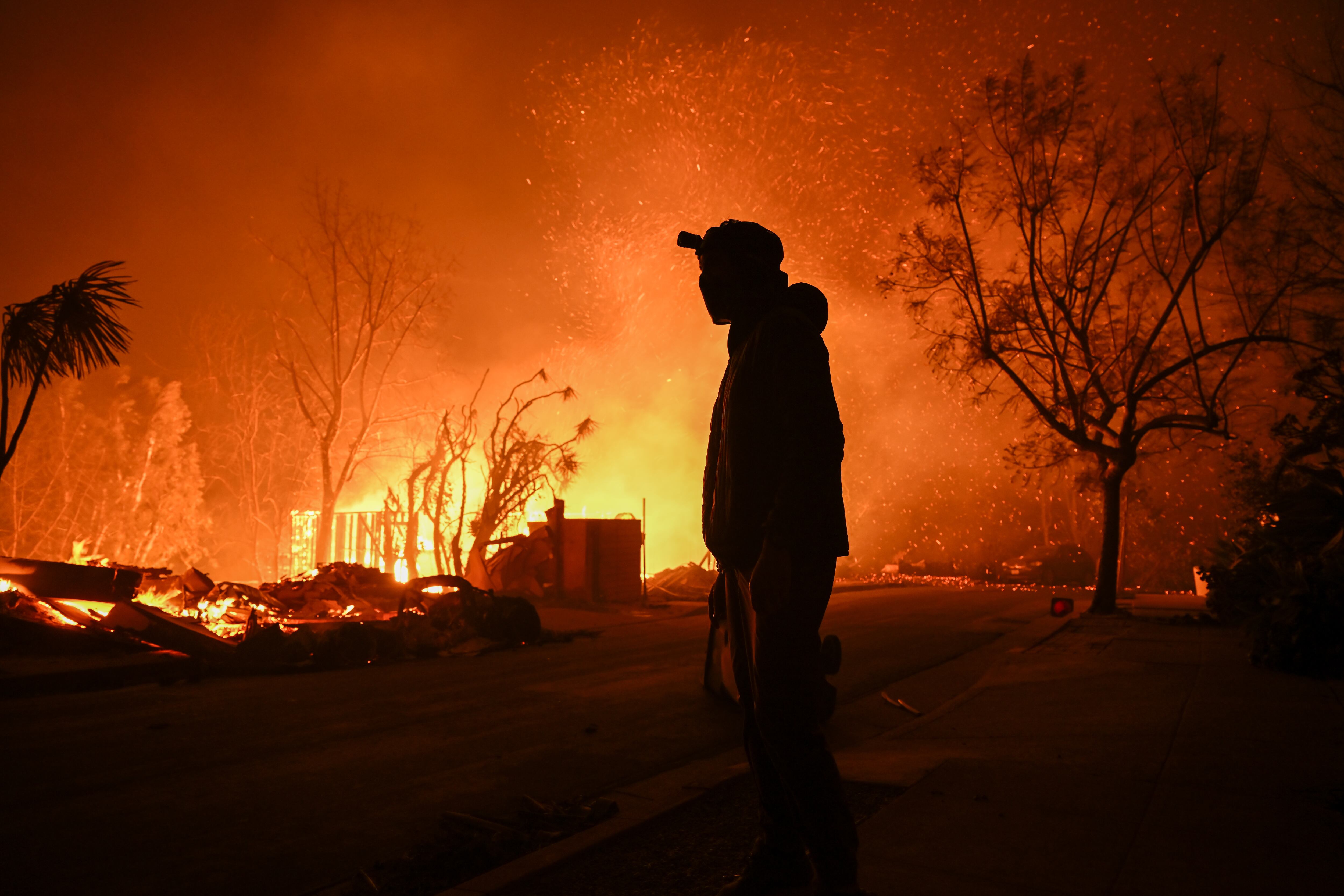 CALIFORNIA, UNITED STATES - JANUARY 8: A house in on fire as residents try to escape the site in Pacific Palisades, California, Los Angeles, United States on January 8, 2025. A fast-moving wildfire has forced 30,000 people to evacuate, with officials warning that worsening winds could further escalate the blaze. (Photo by Tayfun Coskun/Anadolu via Getty Images)