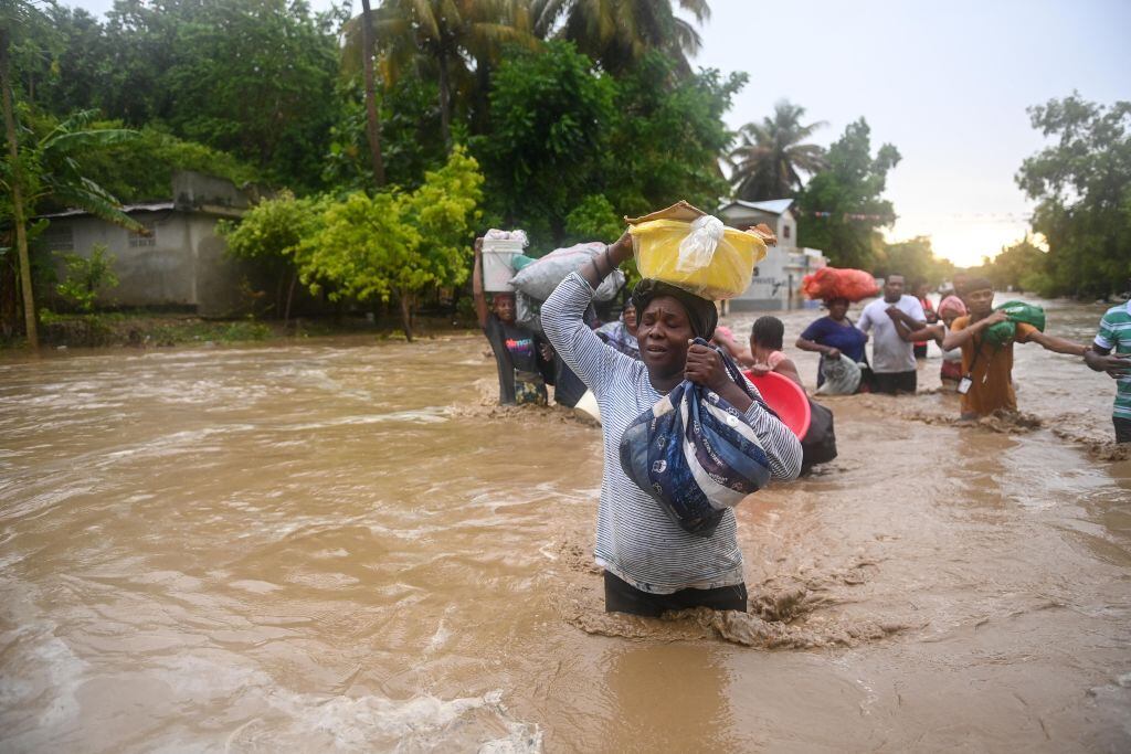 Personas avanzan por el agua que inunda las localidades en Haití