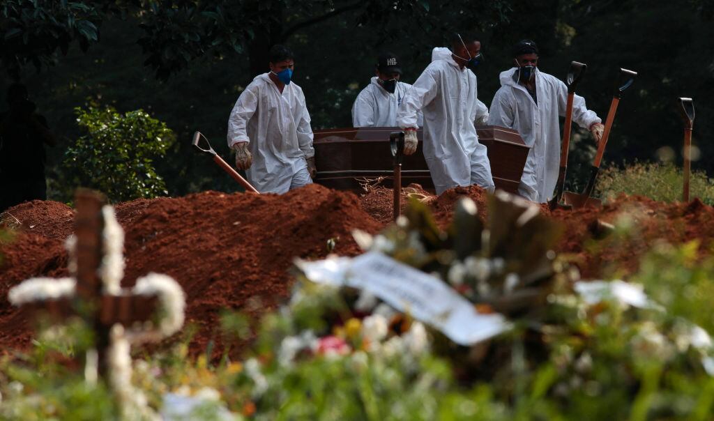 Trabajadores de un cementerio realizan el funeral de una víctima del Covid-19 en Brasil