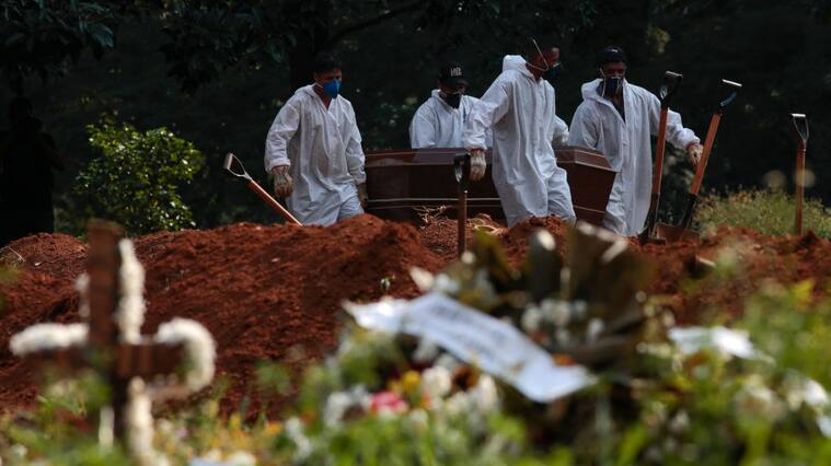 Trabajadores de un cementerio realizan el funeral de una víctima del Covid-19 en Brasil