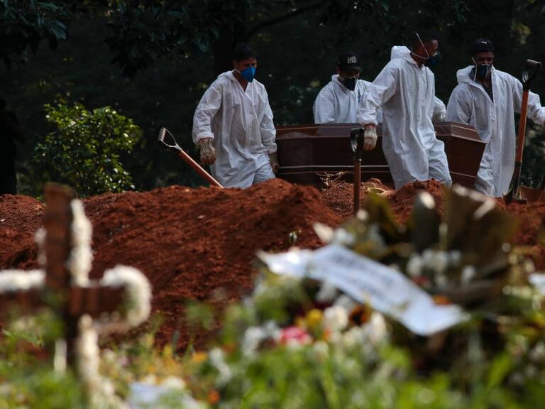 Trabajadores de un cementerio realizan el funeral de una víctima del Covid-19 en Brasil