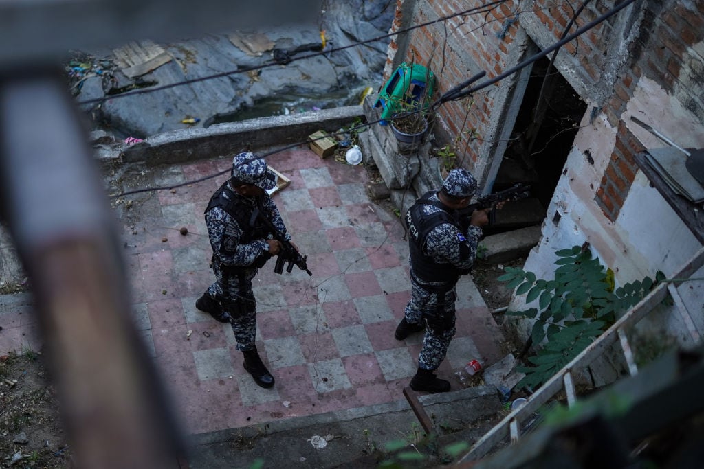 Agentes de las fuerzas de seguridad ingresan armados a una vivienda en un barrio de San Salvador en El Salvador.