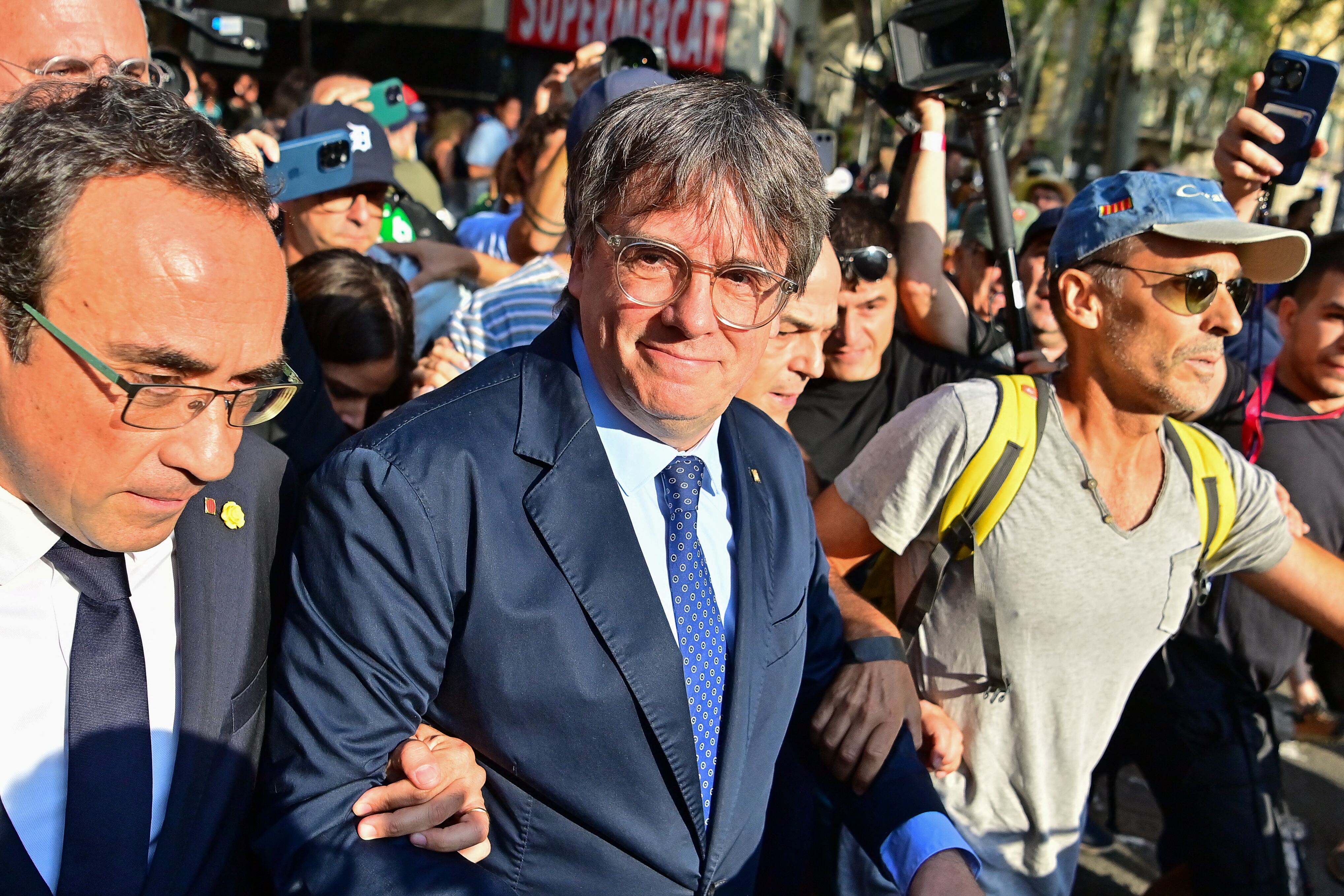 TOPSHOT - Catalonia's exiled separatist leader Carles Puigdemont arrives as his hardline separatist JxCAT party has scheduled a welcome ceremony, ahead of an investiture vote at the Parliament of Catalonia, in Barcelona on August 8, 2024. Catalonia's parliament is set to elect a new leader for the Spanish region, but the planned return of exiled separatist leader Carles Puigdemont even though he faces arrest threatens to derail the event. After months of negotiations following an inconclusive May regional election, the leader of the local branch of Spain's ruling Socialists Salvador Illa is poised to become Catalonia's new leader. But the vote could be upended if Puigdemont -- who fled to Belgium shortly after Catalonia's failed 2017 independence bid to avoid prosecution -- returns to Spain and is arrested. (Photo by MANAURE QUINTERO / AFP) (Photo by MANAURE QUINTERO/AFP via Getty Images)