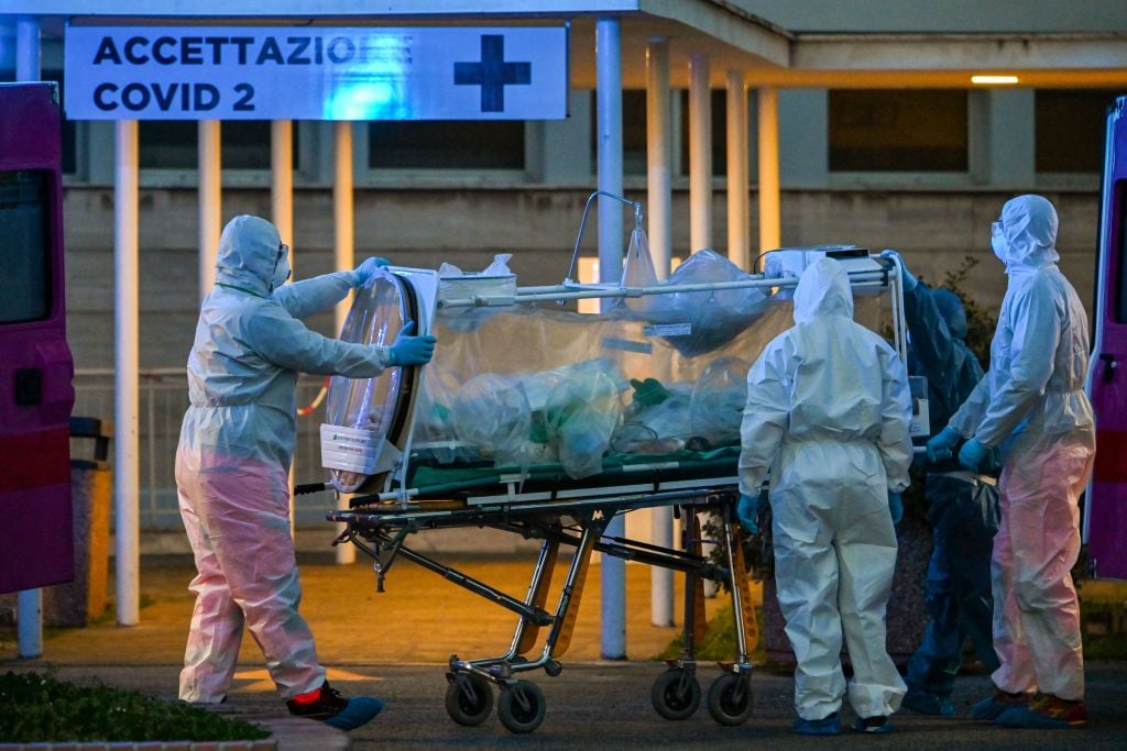 Medical workers in overalls stretch a patient under intensive care into the newly built Columbus Covid 2 temporary hospital to fight the new coronavirus infection, on March 16, 2020 at the Gemelli hospital in Rome. (Photo by ANDREAS SOLARO / AFP) (Photo by ANDREAS SOLARO/AFP via Getty Images)