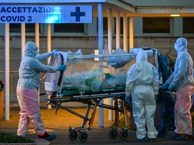 Medical workers in overalls stretch a patient under intensive care into the newly built Columbus Covid 2 temporary hospital to fight the new coronavirus infection, on March 16, 2020 at the Gemelli hospital in Rome. (Photo by ANDREAS SOLARO / AFP) (Photo by ANDREAS SOLARO/AFP via Getty Images)