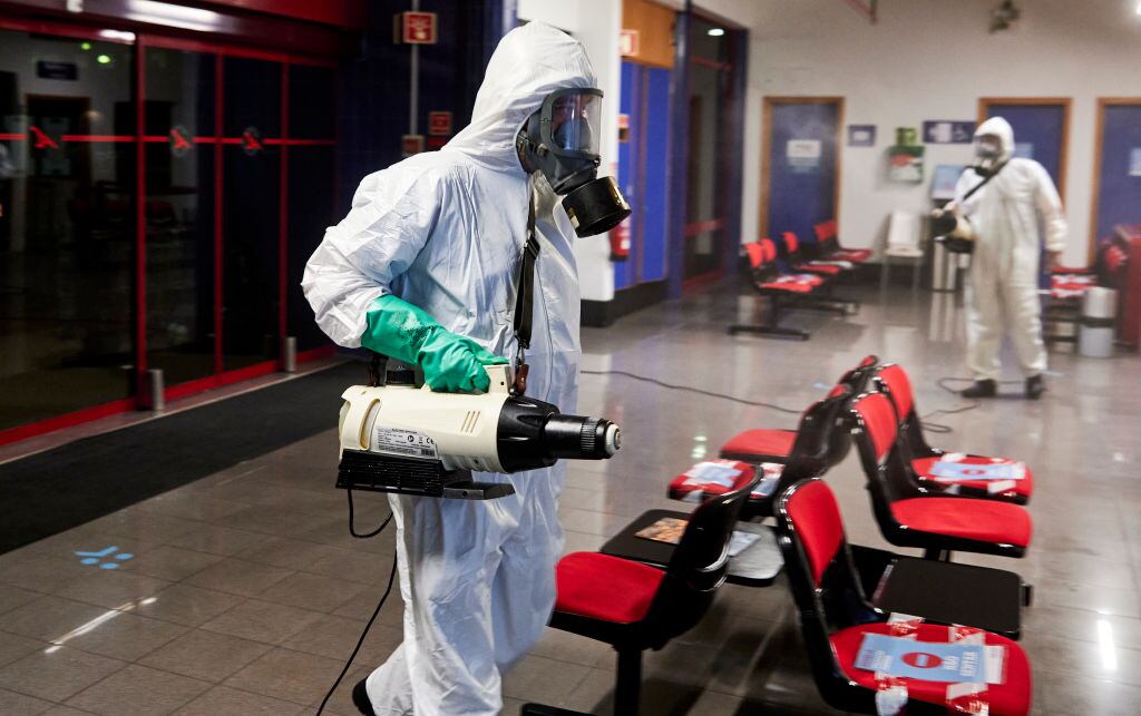 Trabajadores sanitizan un terminal de aeropuerto en Portugal