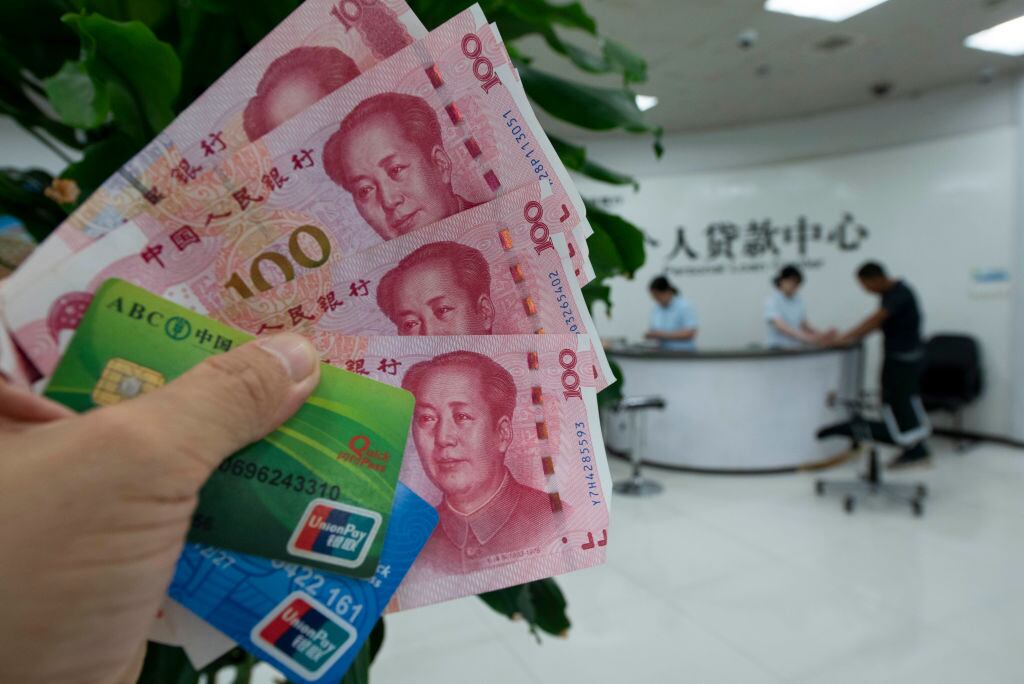 Una persona recibe yuanes y tarjetas de crédito en un banco en Haian de China