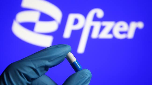 UKRAINE - 2021/10/17: In this photo illustration, a medicine pill is seen in a hand dressed in a medical glove with a Pfizer logo in the background. (Photo Illustration by Pavlo Gonchar/SOPA Images/LightRocket via Getty Images)