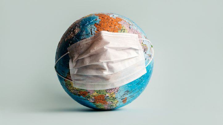 Globe made of jigsaw puzzles with a protective medical mask as a prophylaxis in the fight against coronavirus infection. Measures against the spread of the virus