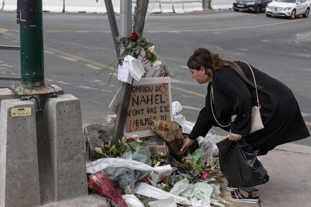 NANTERRE, FRANCE - JULY 1: A woman pays her respects at the site where Nahel M. died, shortly after his funeral, on July 1, 2023 in Nanterre, France. Nahel M., a French teenager of North African origin was shot dead by police on June 27th, the third fatal traffic stop shooting this year in France - causing nationwide unrest and clashes with police forces. (Photo by Sam Tarling/Getty Images)