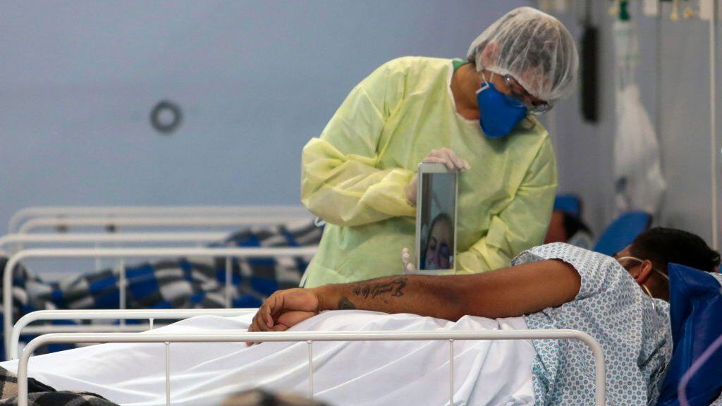 TOPSHOT - A patient affected by the COVID-19 coronavirus speaks with a family member by a video call at a field hospital set up at a sports gym, in Santo Andre, Sao Paulo state, Brazil, on May 11, 2020. (Photo by Miguel SCHINCARIOL / AFP) (Photo by MIGUEL SCHINCARIOL/AFP via Getty Images)