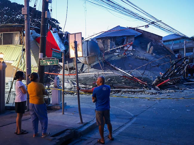 GENERAL SANTOS, PHILIPPINES - JUNE 8: People gather near a collapsed Jolibee fast food restaurant next to a church, following a magnitude 7.8 earthquake that struck the Southern Philippines, in General Santos city, Philippines, on June 8, 2026. Numerous buildings and structures have been destroyed or collapsed after the powerful earthquake hit the Mindanao region in the Southern Philippines on the morning of June 8 local time, killing at least 15 people and injuring more than 100. Rescue operations are underway. (Photo by Daniel Ceng/Anadolu via Getty Images)