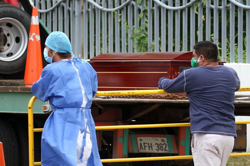 Dos personas suben féretros a un vehículo en la ciudad de Guayaquil