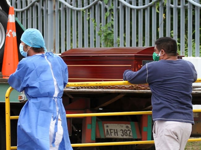 Dos personas suben féretros a un vehículo en la ciudad de Guayaquil