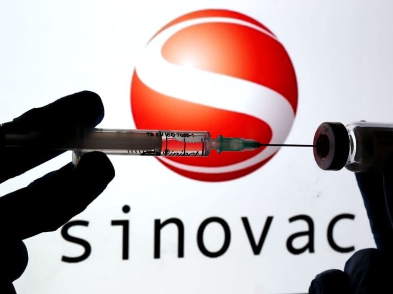 ANKARA, TURKEY - DECEMBER 16: In this photo illustration taken in Ankara, Turkey on December 16, 2020 Sinovac logo is displayed on a screen with a hand holdign a syringe in the front. (Photo by Mehmet Kaman/Anadolu Agency via Getty Images)