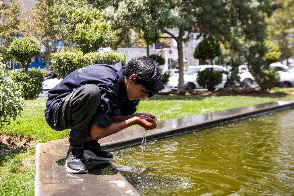 Niño bebe agua de una fuente de Teherán en Irán
