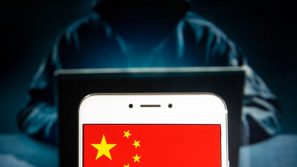 HONG KONG - 2019/04/05: In this photo illustration a People's Republic of China flag is seen on an Android mobile device with a figure of hacker in the background. (Photo Illustration by Budrul Chukrut/SOPA Images/LightRocket via Getty Images)