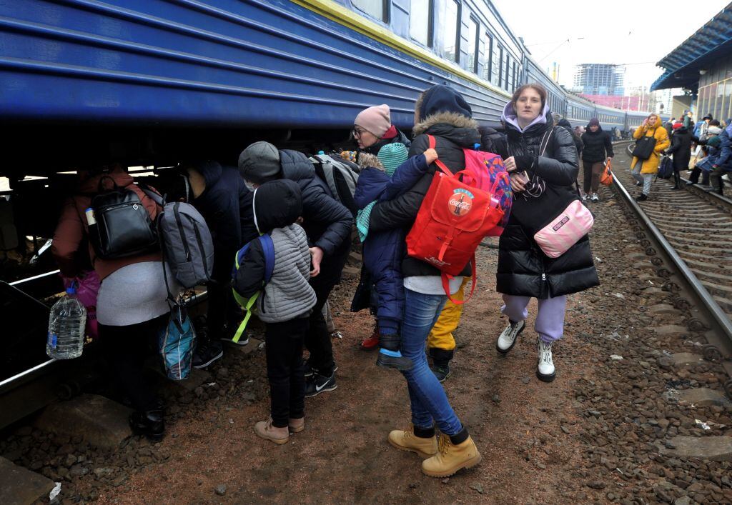 Personas caminan en las vías para abordar un tren que los saque de Kiev