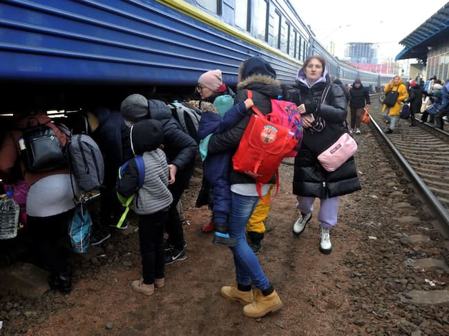 Personas caminan en las vías para abordar un tren que los saque de Kiev