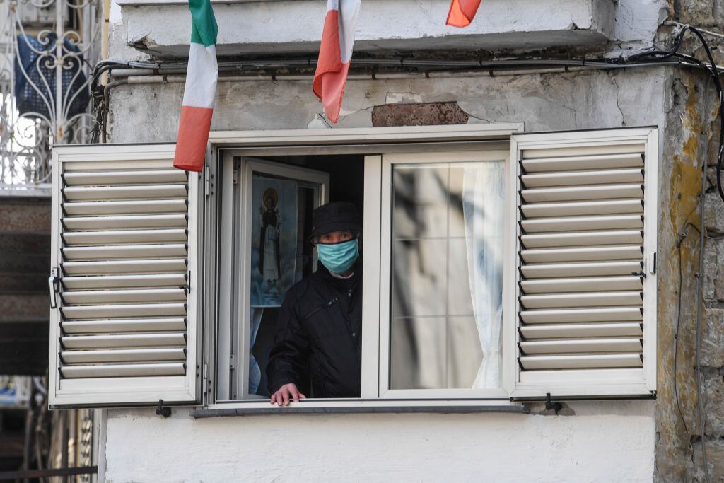 Un adulto mayor observa por una ventana durante la cuarentena en la ciudad italiana de Nápoles