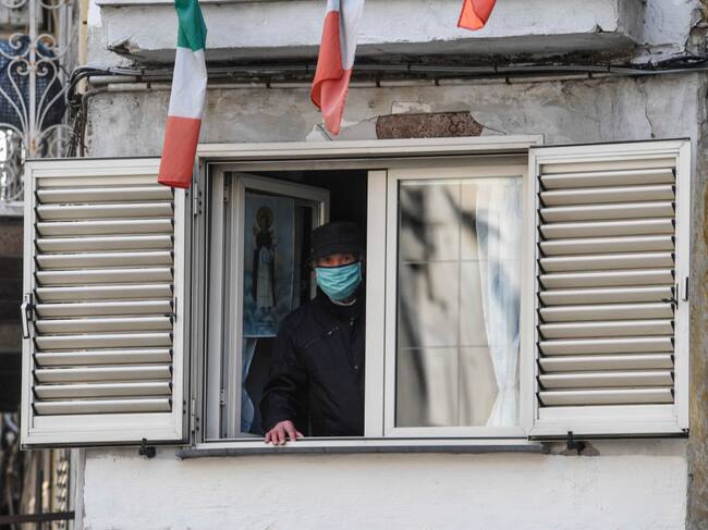 Un adulto mayor observa por una ventana durante la cuarentena en la ciudad italiana de Nápoles