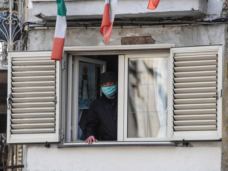 Un adulto mayor observa por una ventana durante la cuarentena en la ciudad italiana de Nápoles