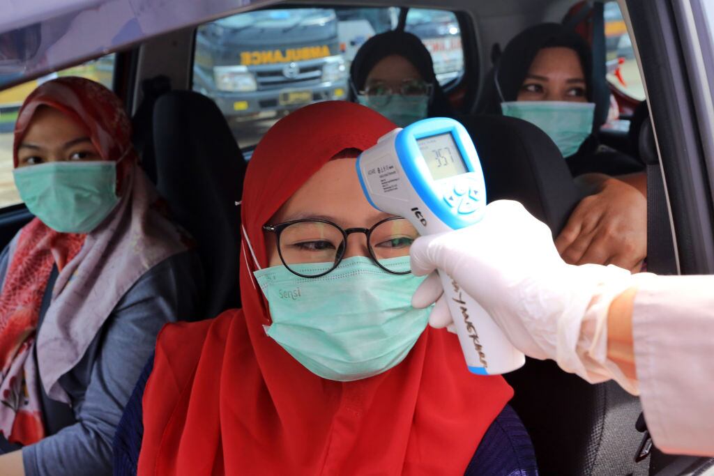 La policía mide la temperatura de una familia en Indonesia