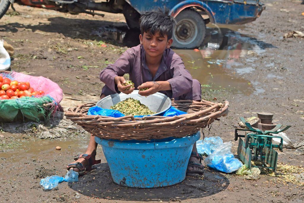 Un niño vende verduras en un mercado de Pakistán