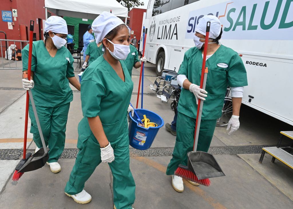 Unas trabajadoras sanitizan un barrio de la ciudad de Lima