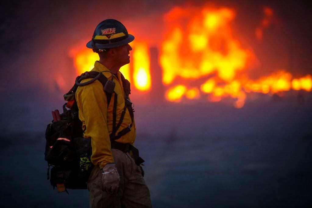 Un brigadista observa la fuerza del fuego cerca de un barrio de Louisville