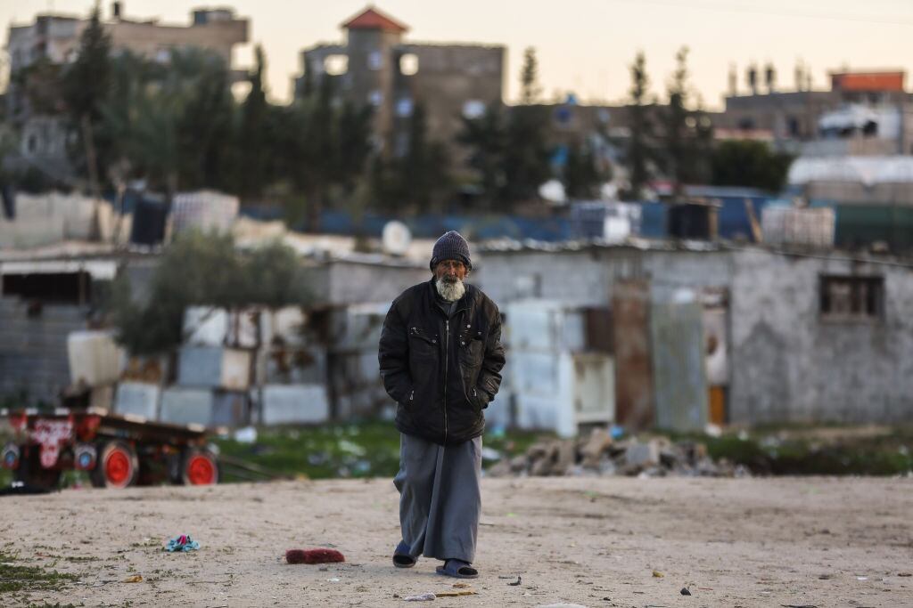 Un adulto mayor camina ante los escombros que dejan los ataques de Israel y en medio de un campo de refugiados en el sur de la Franja de Gaza.