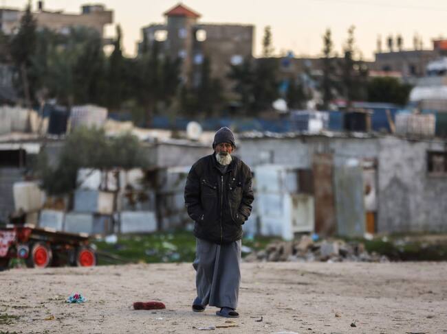 Un adulto mayor camina ante los escombros que dejan los ataques de Israel y en medio de un campo de refugiados en el sur de la Franja de Gaza.