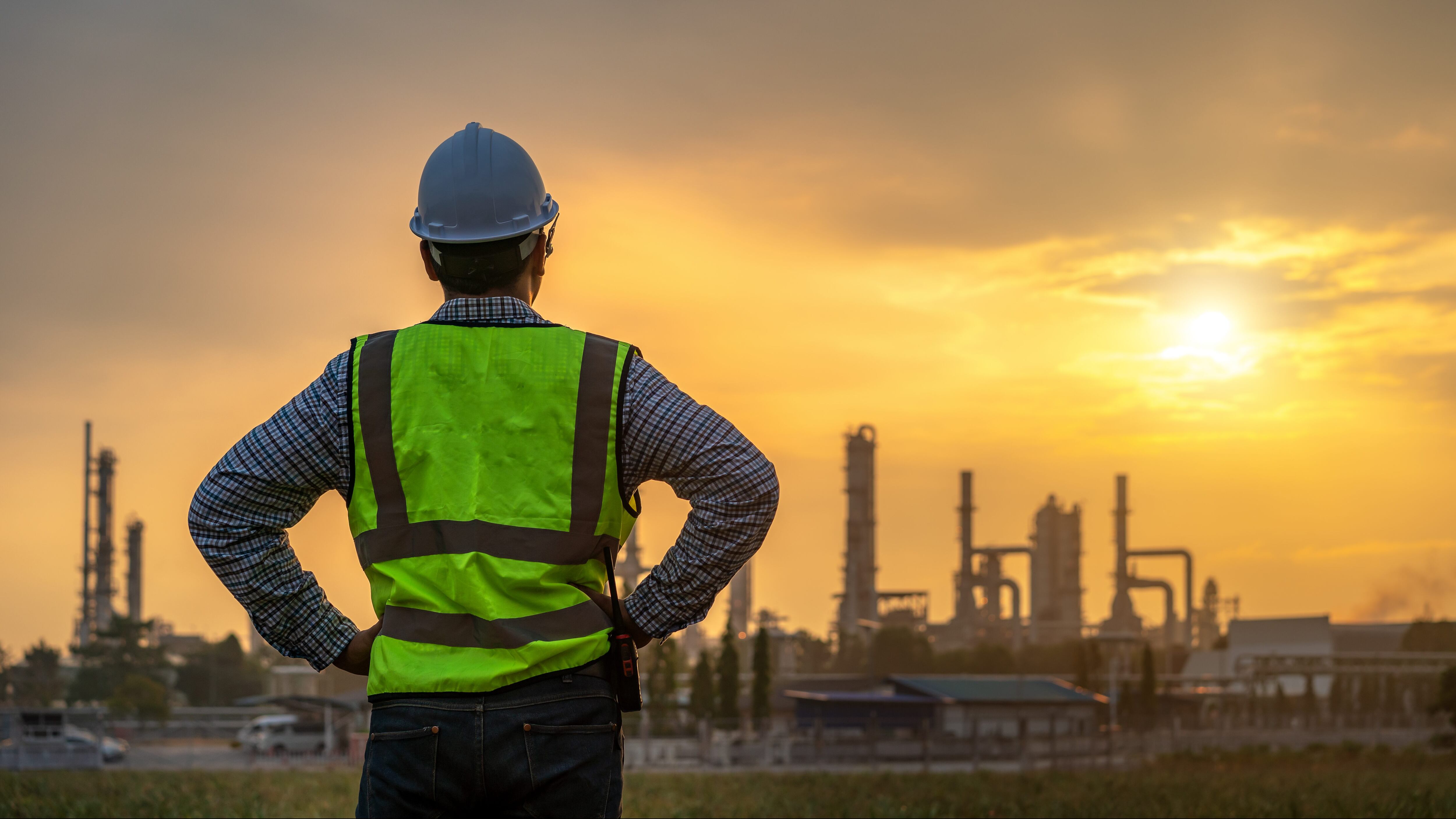 Asian engineers looking at site in oil and gas refinery or Petrochemical factory during sunrise, industrial concept.