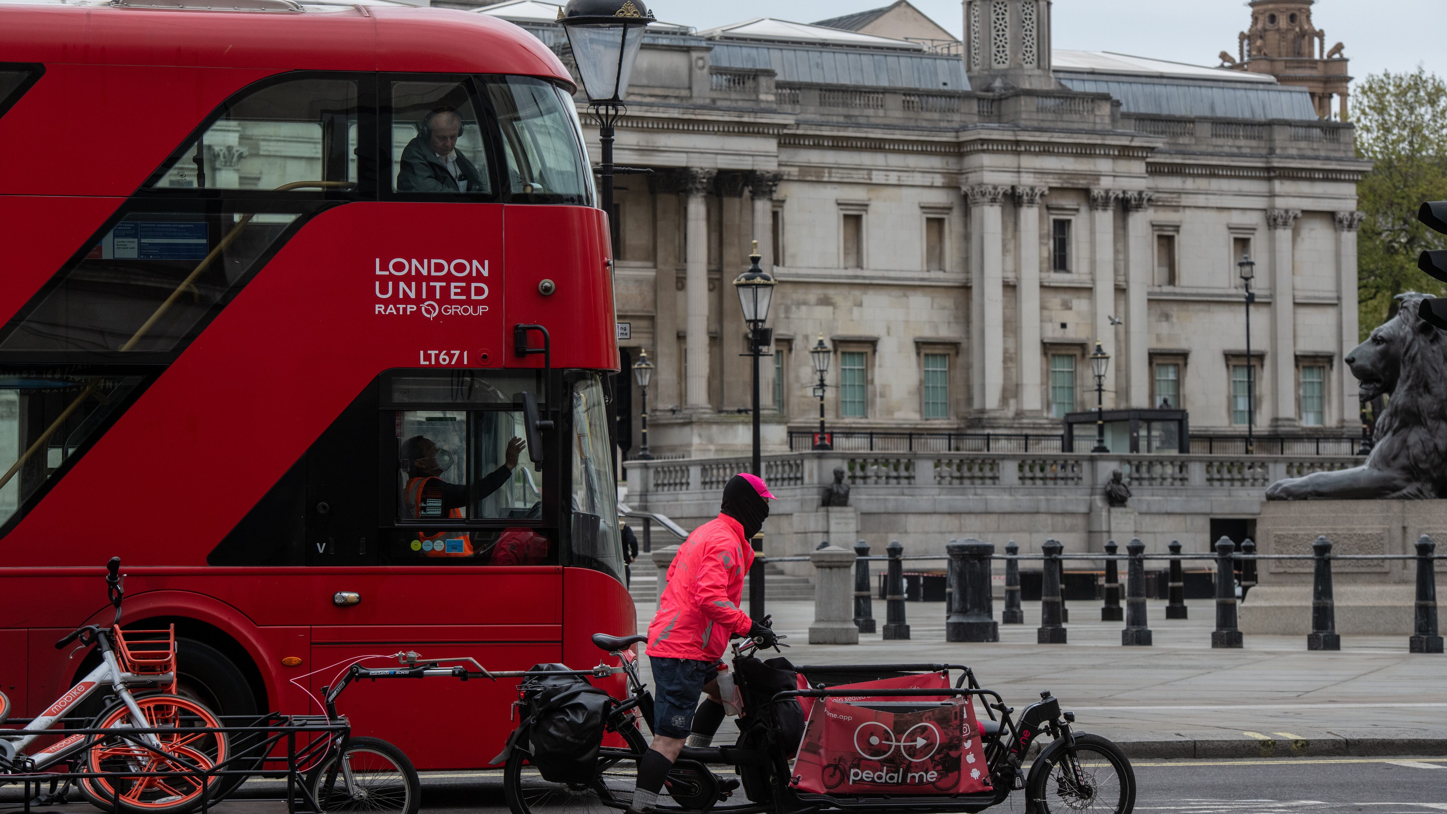 LONDON, ENGLAND - APRIL 17 : A bus driver wears a face mask whilst driving past Trafalgar Square on April 17, 2020 in London, United Kingsom. In a press conference on Thursday, First Secretary of State Dominic Raab announced that the lockdown will remain in place for at least 3 more weeks. The Coronavirus (COVID-19) pandemic has spread to many countries across the world, claiming over 140,000 lives and infecting more than 2 million people. (Photo by Chris J Ratcliffe/Getty Images)