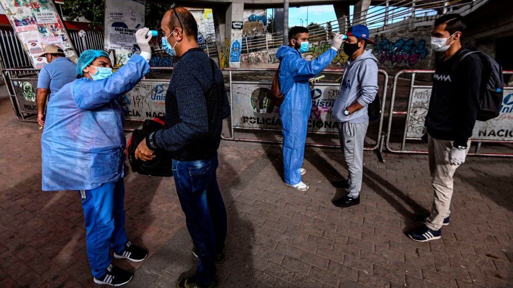 TOPSHOT - People wear face masks as they get their temperature checked by health workers wearing protective suits as a preventive measure against the spread of the new coronavirus in Bogota, on April 2, 2020. - More than 20,000 cases of COVID-19 were registered in Latin America and the Caribbean by Wednesday -- double the figure from five days ago, according to an AFP tally. (Photo by Juan BARRETO / AFP) (Photo by JUAN BARRETO/AFP via Getty Images)