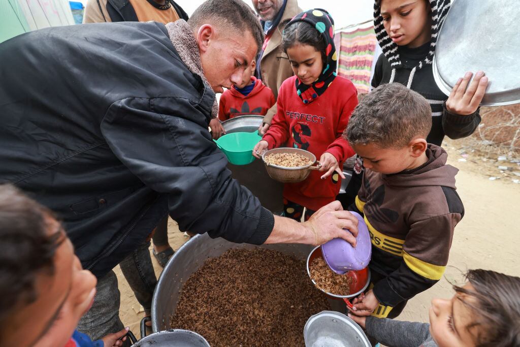 Voluntarios entregan alimentos a un grupo de niños palestinos refugiados en la zona de Rafah por los ataques de Israel, al sur de la Franja de Gaza en Palestina.