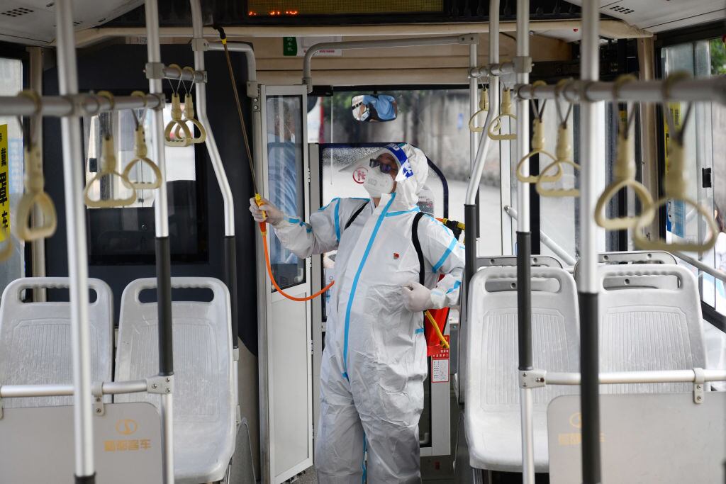 Trabajadores desinfectan un bus del transporte en la ciudad de Chengdu