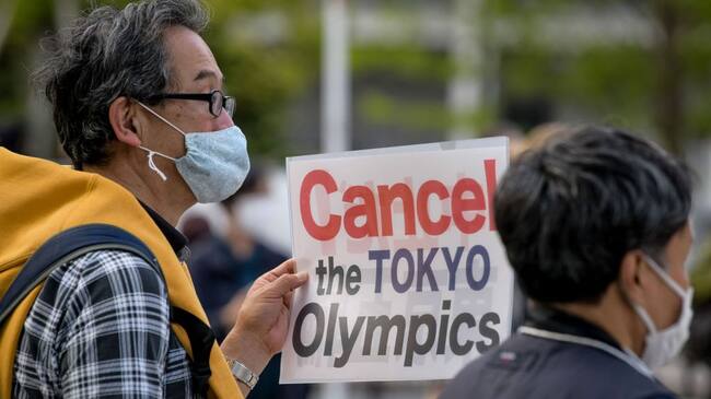 TOKYO, JAPAN - 2021/05/09: A protester carries a placard during a demonstration against the Tokyo Olympics in front of the New National Stadium, the main stadium for the Tokyo Olympics.With less than 3 months remaining until the opening of the Tokyo 2020 Olympics concern continues to linger in Japan over the feasibility of hosting such a huge event during the ongoing COVID-19 pandemic. (Photo by Cezary Kowalski/SOPA Images/LightRocket via Getty Images)