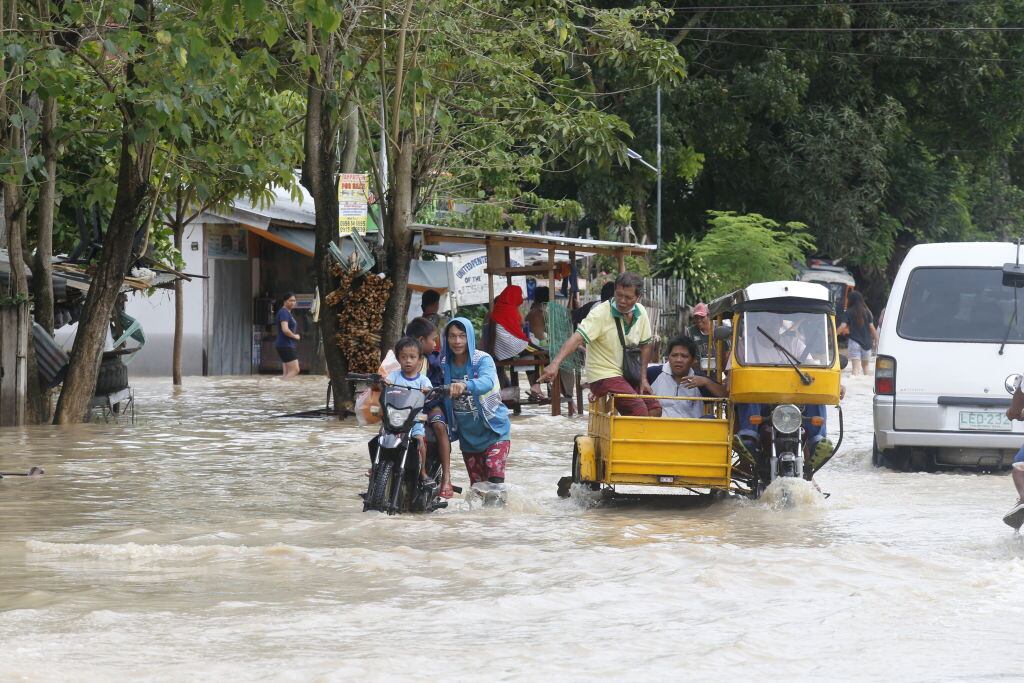 Las personas caminan por el agua tras las inundaciones en Filipinas