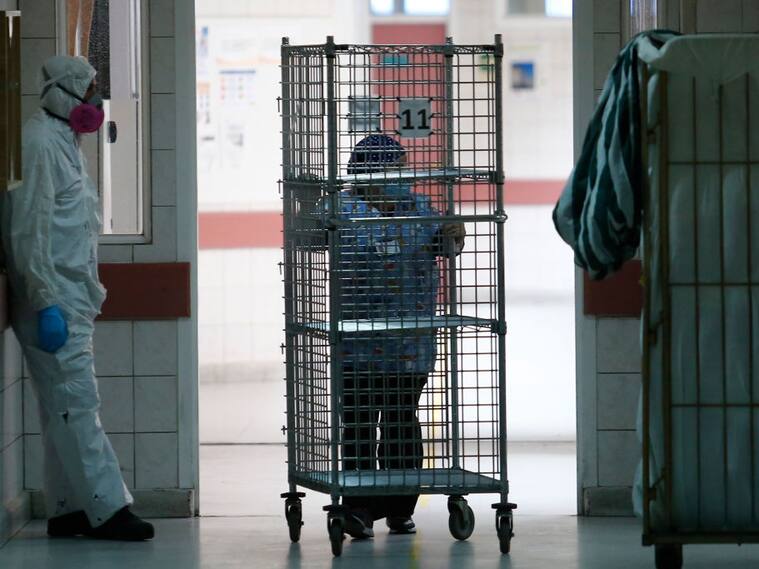 SANTIAGO, CHILE - JUNE 16: Health worker rests as a team member carries supplies during the coronavirus pandemic at San Jose Hospital on June 16, 2020 in Santiago, Chile. On Monday, President Piñera extended the State of Catastrophe for 90 days to better control the outbreak of COVID-19 in the country. (Photo by Marcelo Hernandez/Getty Images)